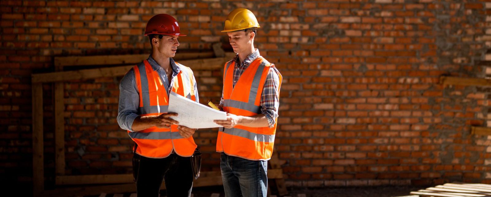 Two men discussing blueprints at a job site
