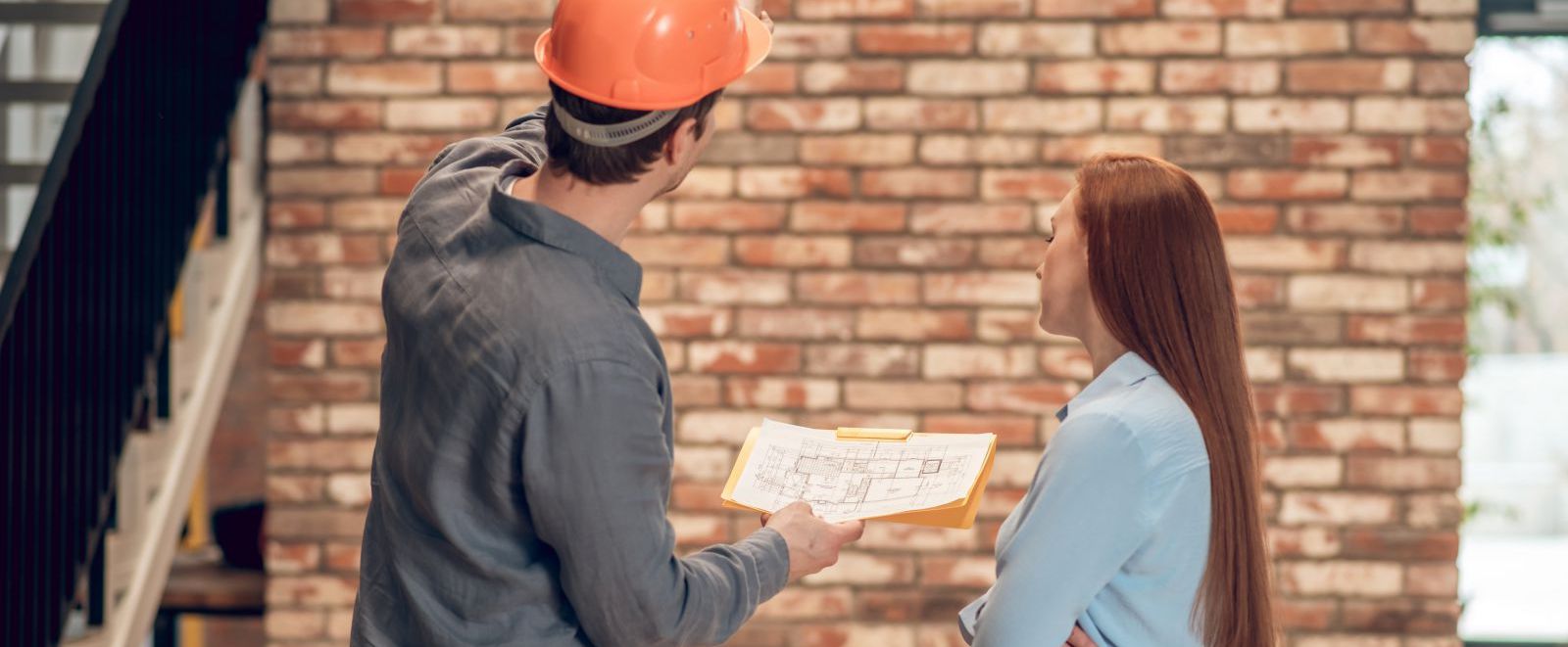 Man and woman discussing blueprints at a work site